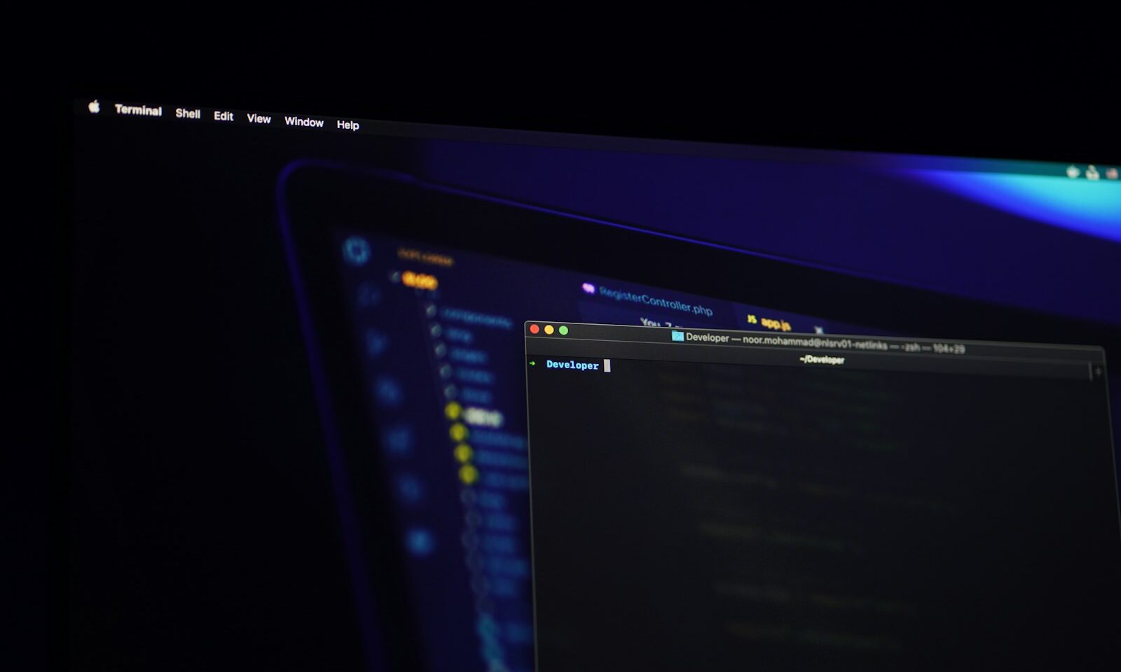 Multiple computer screens displaying software code in a dark developer workspace