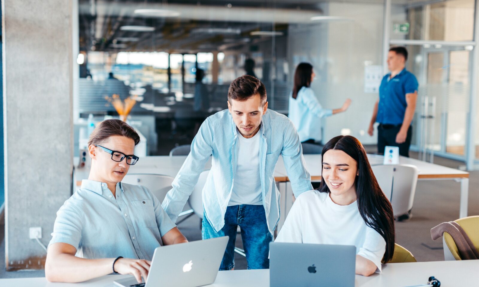 Illustrative photo of professionals collaborating around laptops in an office