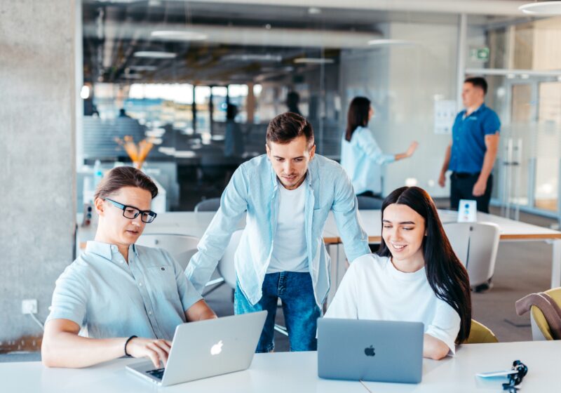 Illustrative photo of professionals collaborating around laptops in an office