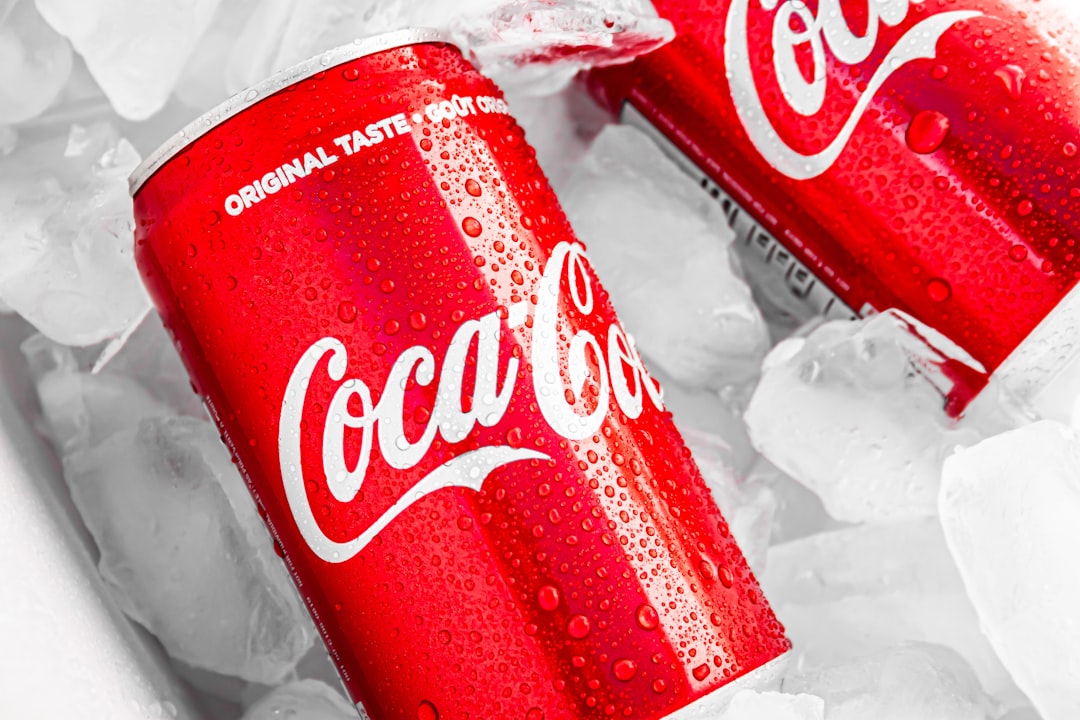 Coca-Cola bottles and cans on ice, showing the brand's distinctive red-and-white visual identity.