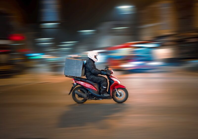 Delivery courier carrying food orders through a city, illustrating DoorDash's multimodal logistics network.