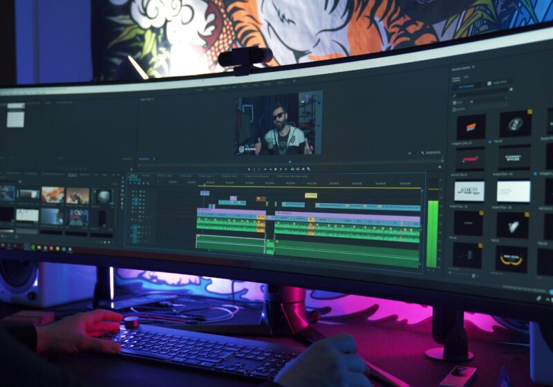 A video editor works at a multimonitor workstation, illustrating AI media production workflows.