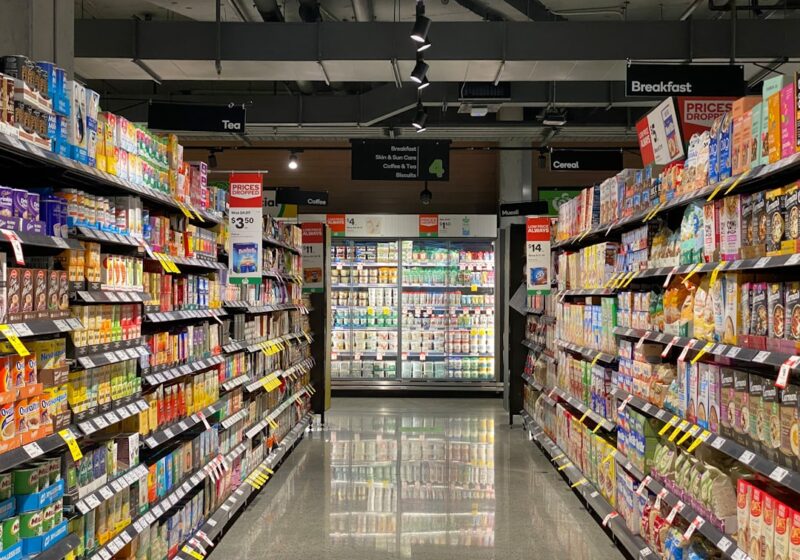 A brightly lit supermarket aisle lined with packaged food and beverage products.