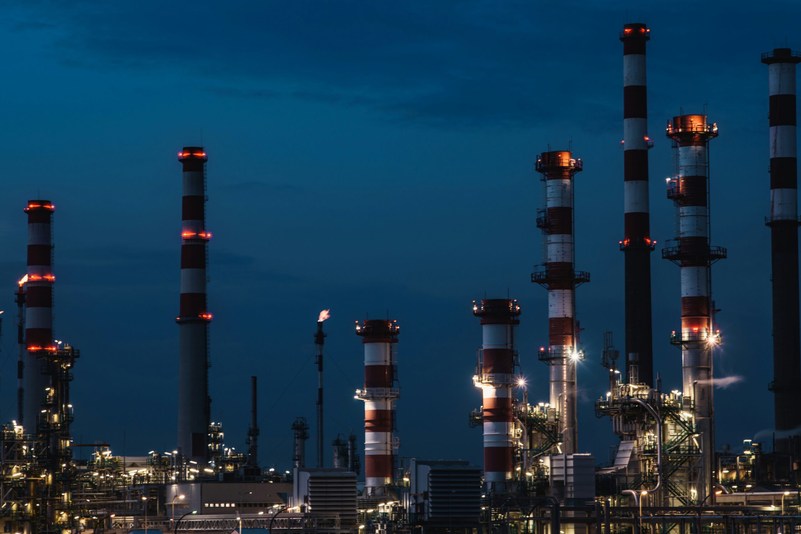 Industrial energy facility with stacks and metal structures under a blue sky.