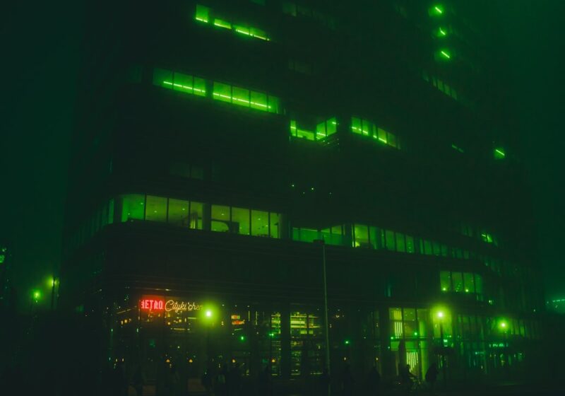 Building illuminated in green at night, illustrating the grounded mystery atmosphere of HBO's Lanterns.