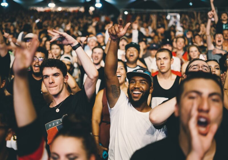 Large music festival crowd facing a brightly lit stage, illustrating Outside Lands as both a physical and livestreamed event.
