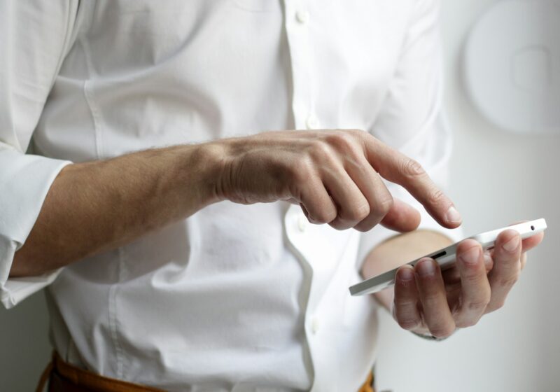 Person using a smartphone beside a laptop, illustrating digital news discovery