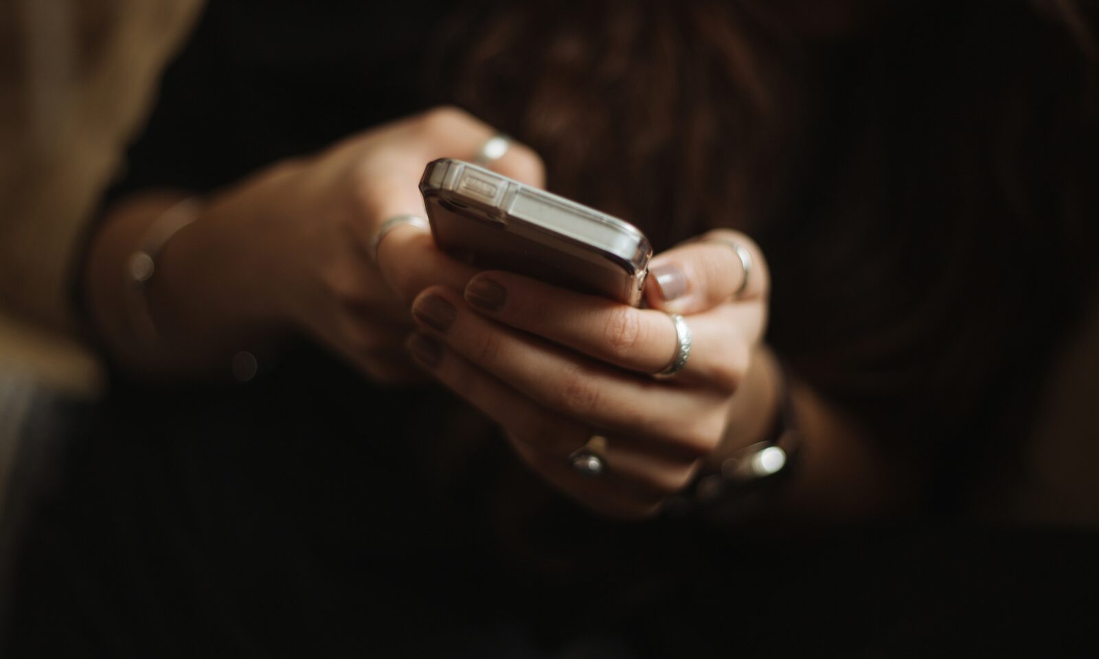 Illustrative image of a person using a smartphone beside a laptop