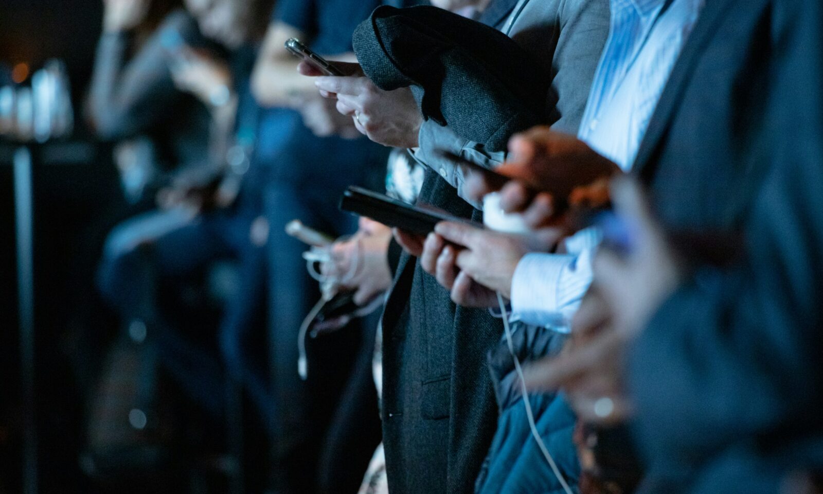 People standing together while looking at smartphones