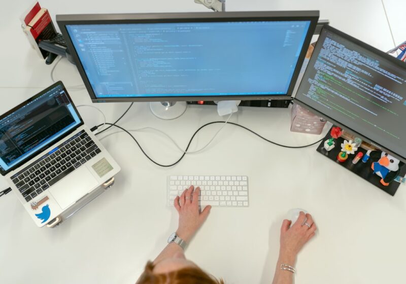 Software engineer working at multiple computer screens in an office