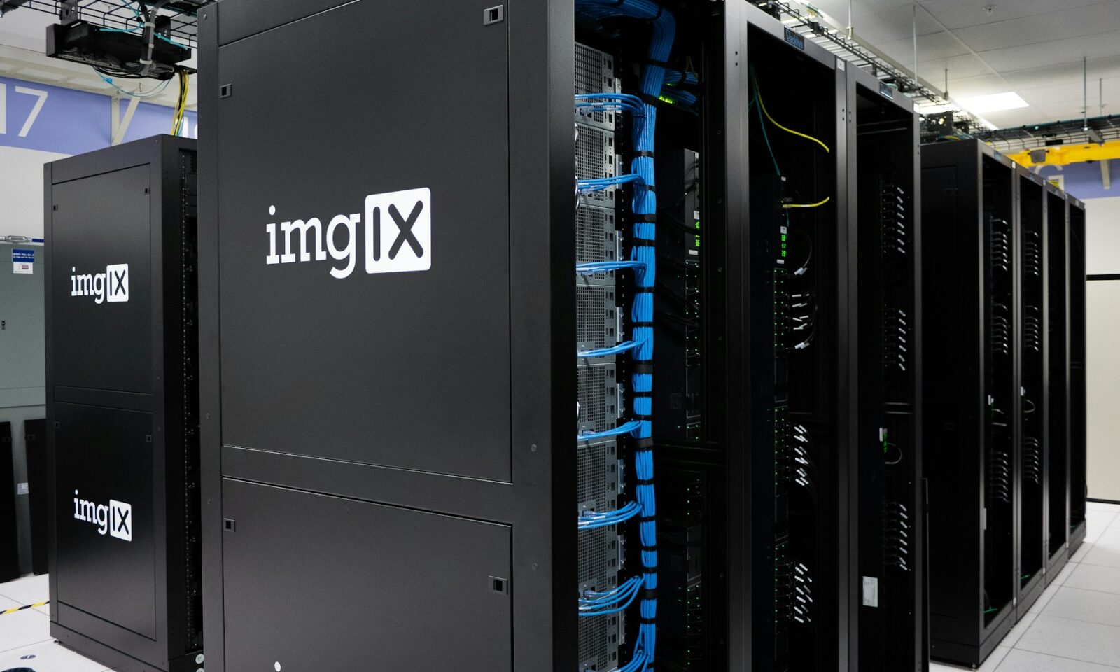 Rows of black server racks with blue network cables in a data center