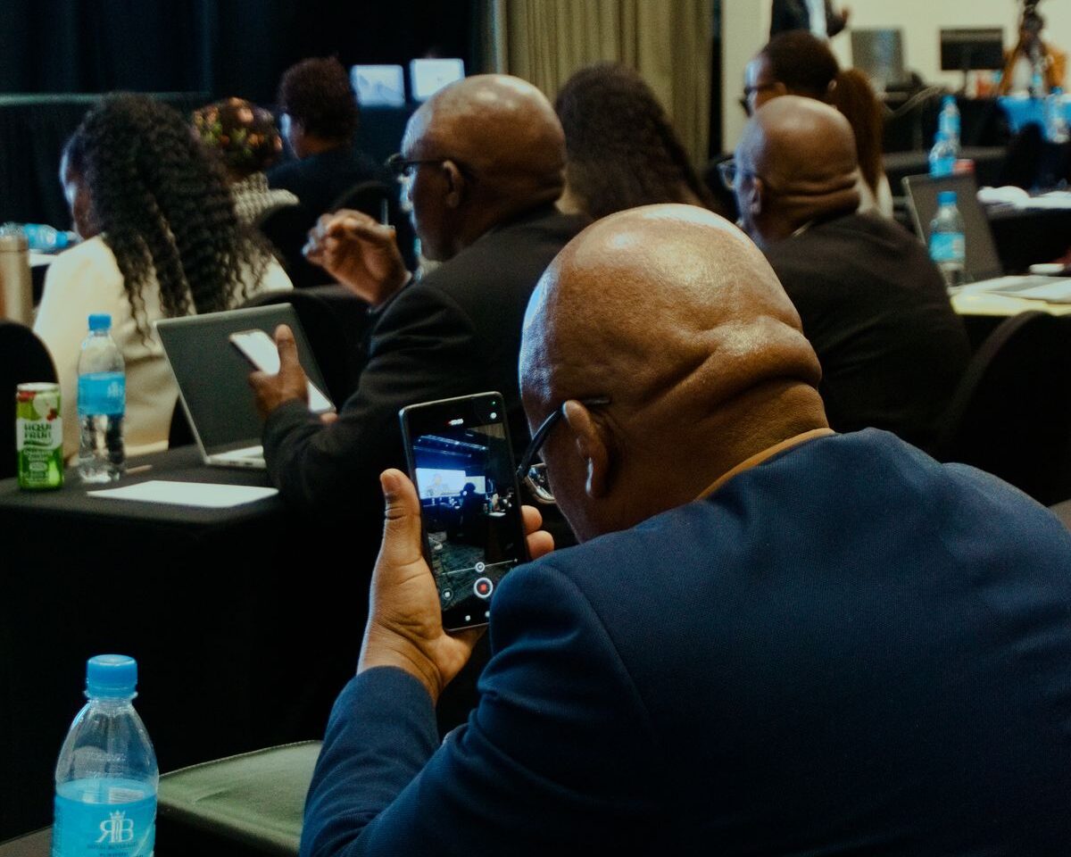 Conference attendee recording a speaker on a mobile phone.