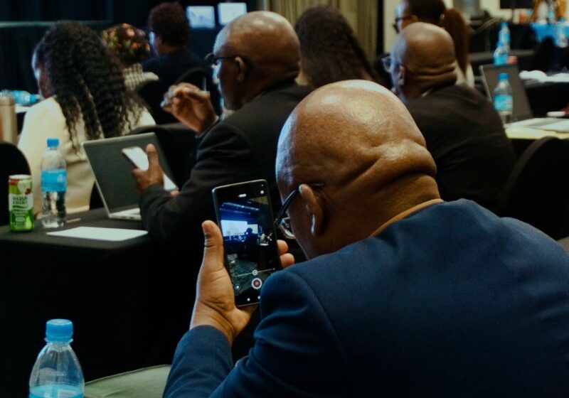 Conference attendee recording a speaker on a mobile phone.