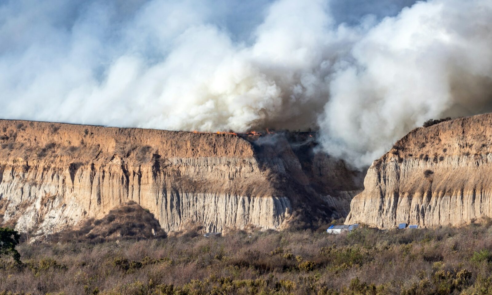 A large plume of wildfire smoke rising over a California mountainside