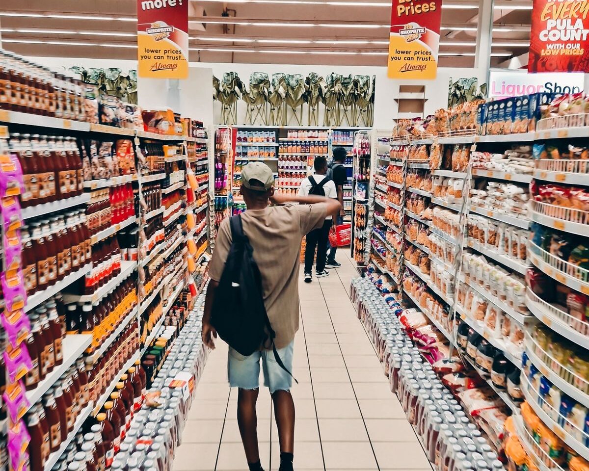 Shopper walking through a brightly stocked grocery aisle.