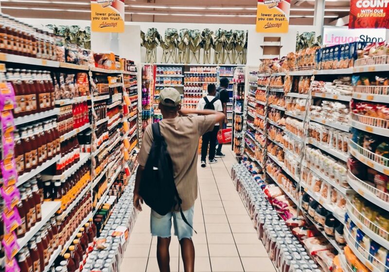 Shopper walking through a brightly stocked grocery aisle.