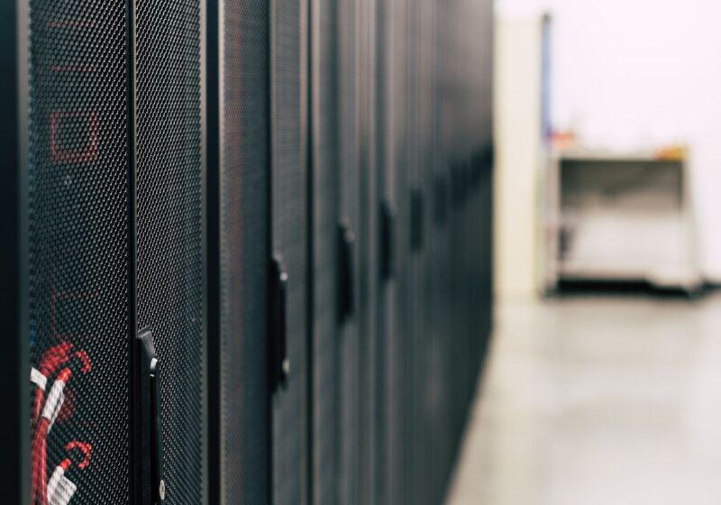 A row of black server cabinets with red cabling.