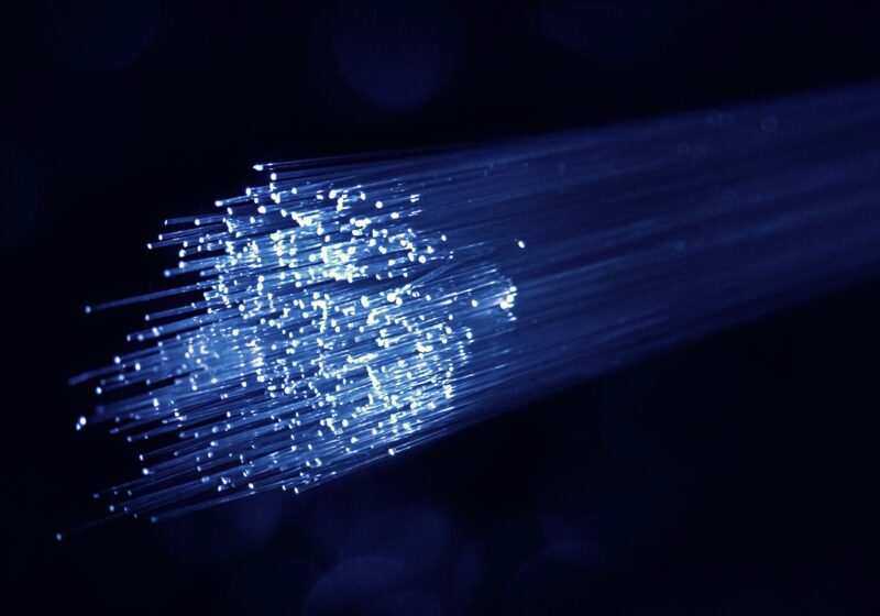 Illuminated fiber-optic strands against a dark blue background