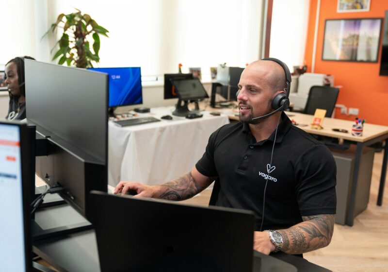 Customer support professional wearing a headset at a computer, illustrating AI-assisted service