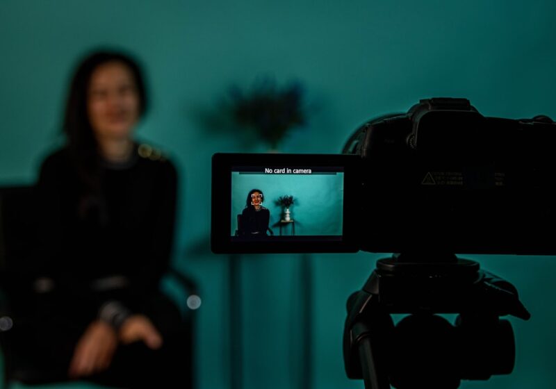 A digital creator filming with a camera, illustrating IMDb's new professional category for online creators.