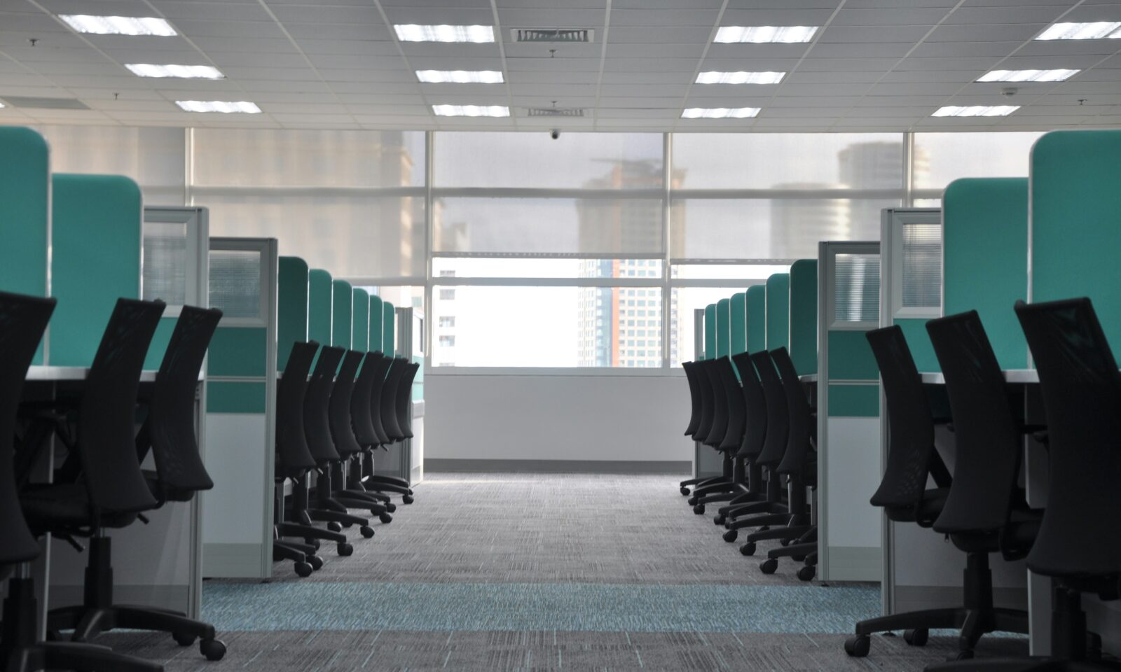 Rows of empty office desks and chairs in an open workplace