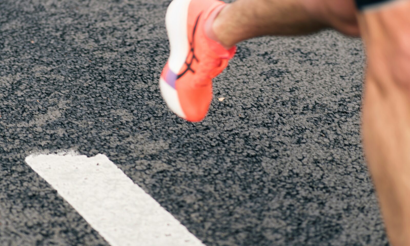 Runner's shoe crossing a white line on a track; illustrative image, not an On product.