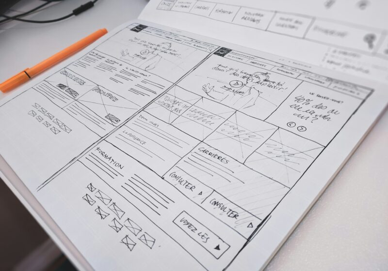 Hand-drawn website wireframe and orange pen on a desk