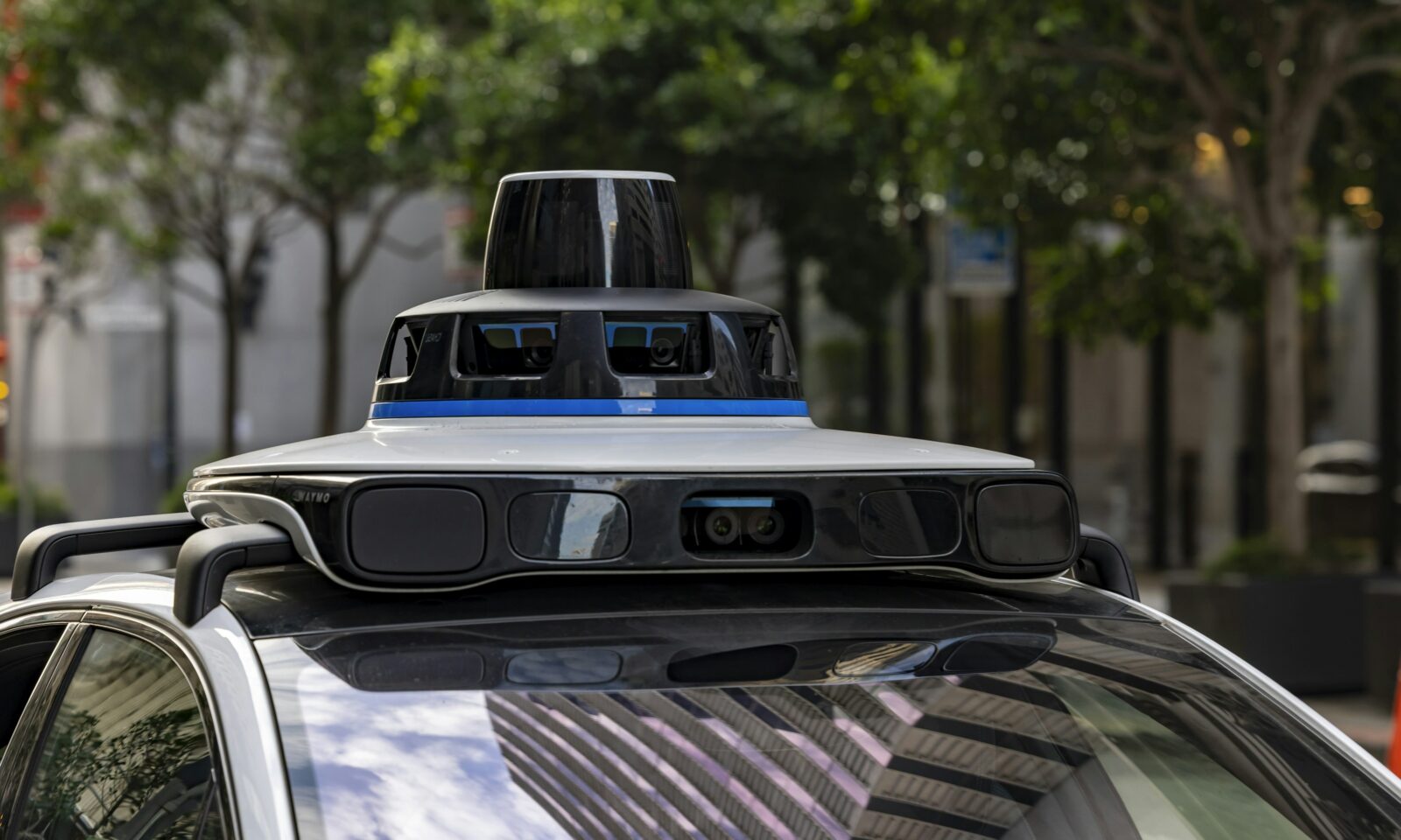 A Waymo autonomous vehicle with rooftop sensors on a city street