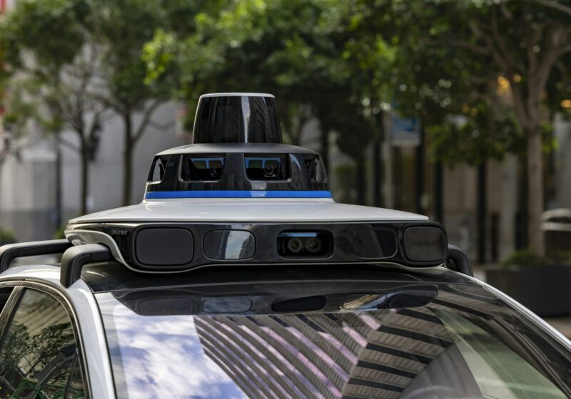 A Waymo autonomous vehicle with rooftop sensors on a city street