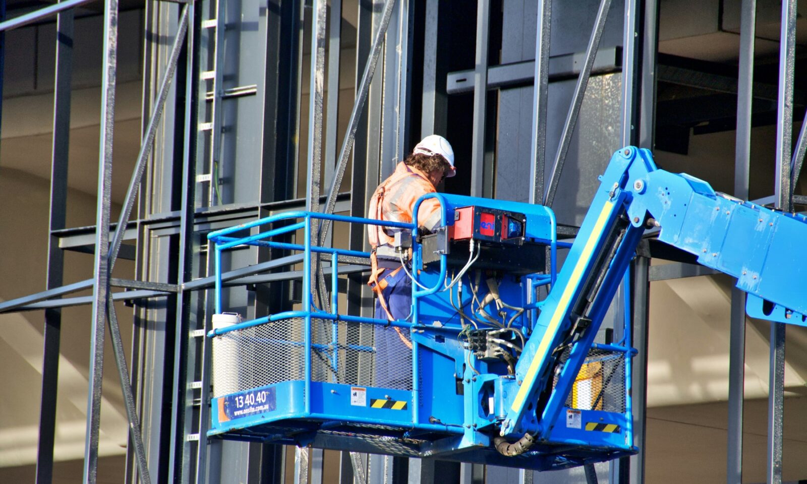 Construction worker operating a lift beside the frame of a building