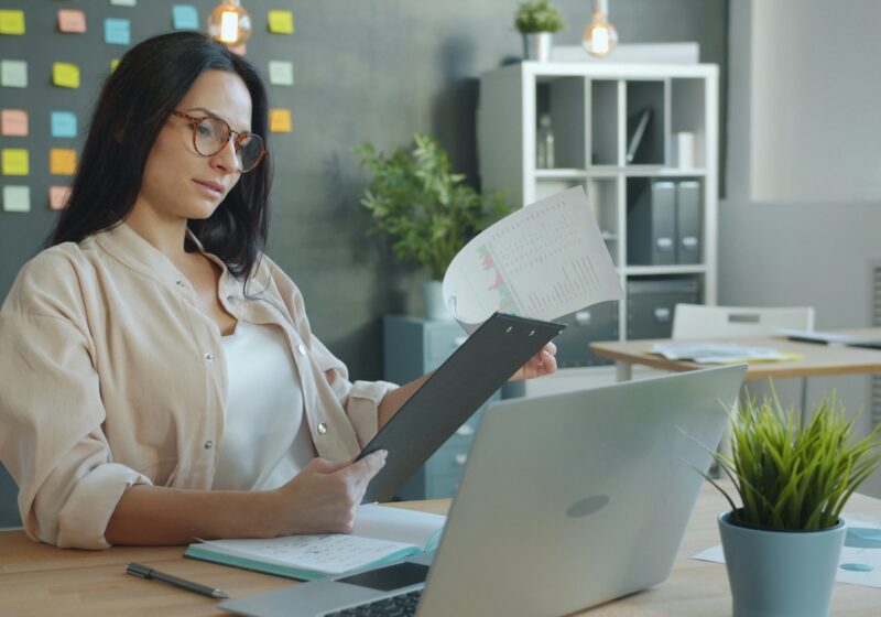 Professional reviewing printed documents beside a laptop, illustrating service-request processing