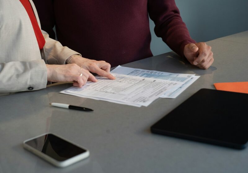 Two professionals reviewing documents at a conference table, illustrating AI governance