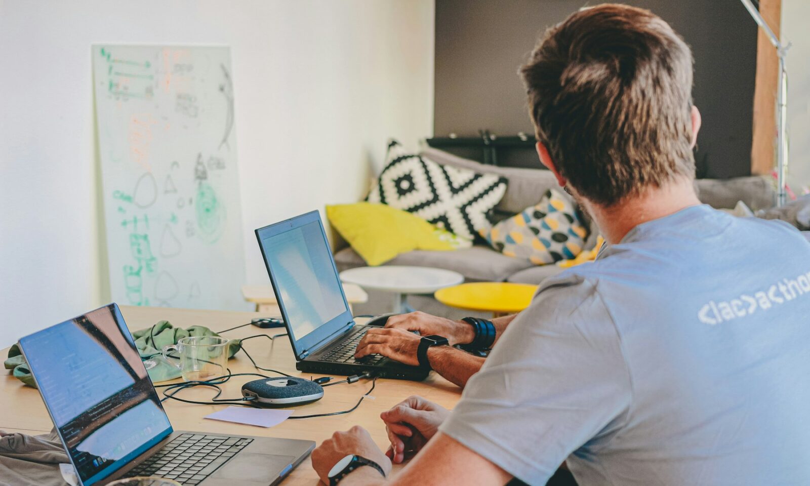 Professional working across two laptop computers, illustrating enterprise AI management