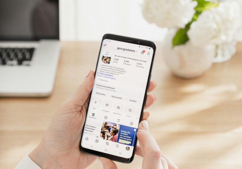Person holding a smartphone displaying a social media profile