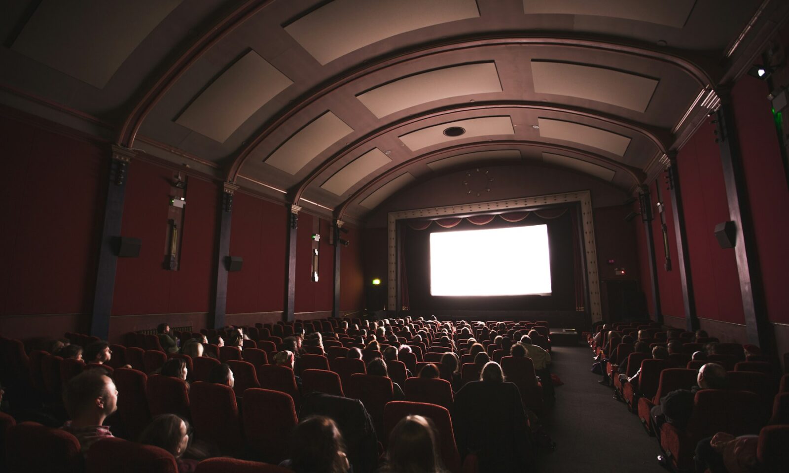 Audience seated in a cinema facing a bright movie screen