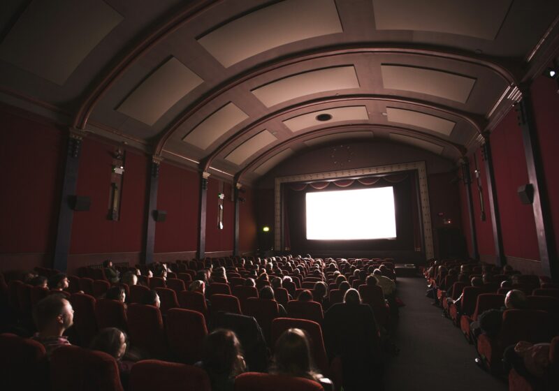 Audience seated in a cinema facing a bright movie screen