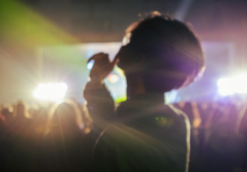 Silhouetted concertgoer facing bright stage lights at a live music performance