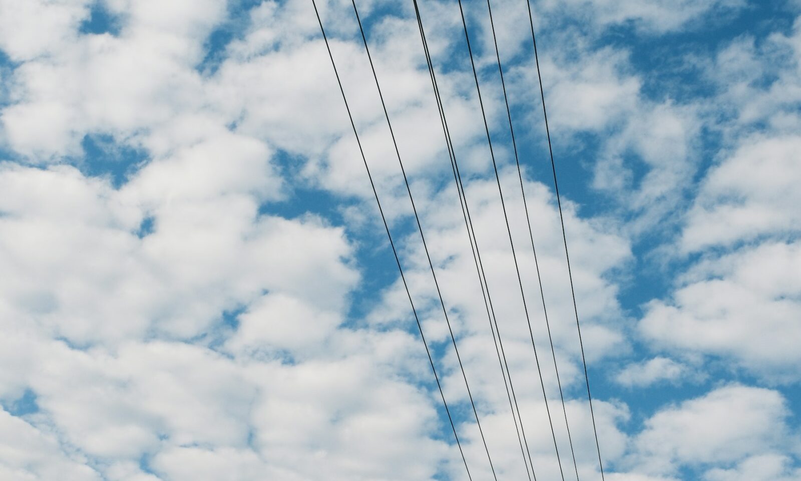Power lines against a cloudy blue sky, illustrating the electricity infrastructure behind AI data centers