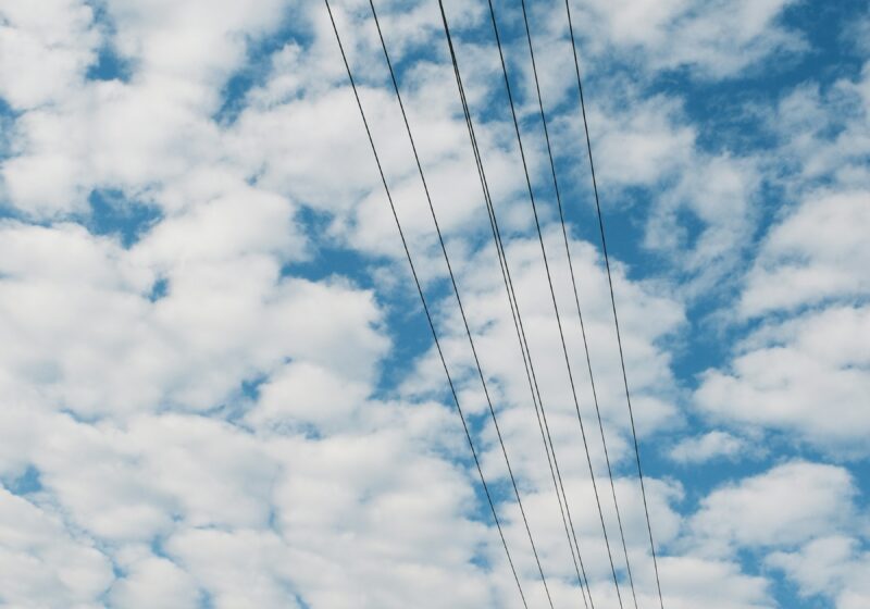 Power lines against a cloudy blue sky, illustrating the electricity infrastructure behind AI data centers