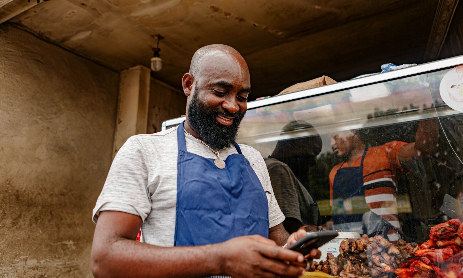 Street-food vendor in Tanzania looking at a smartphone