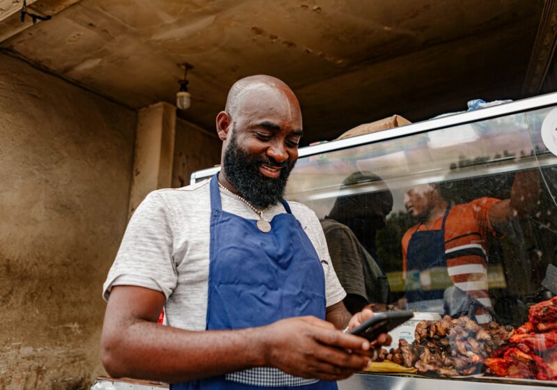 Street-food vendor in Tanzania looking at a smartphone