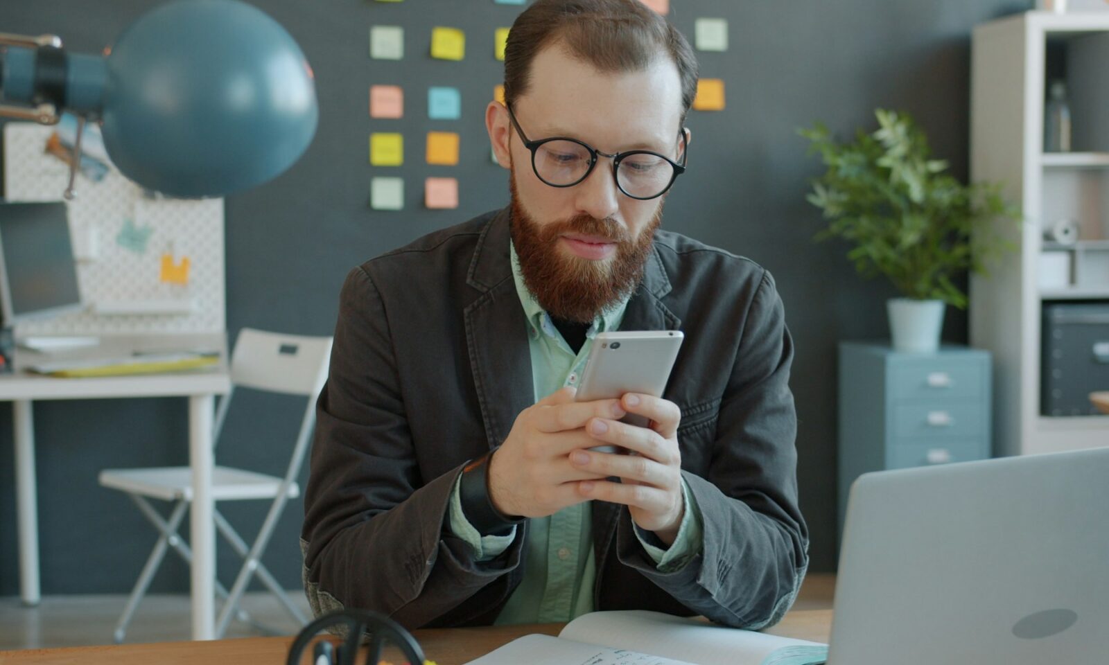 Professional using a smartphone at an office desk