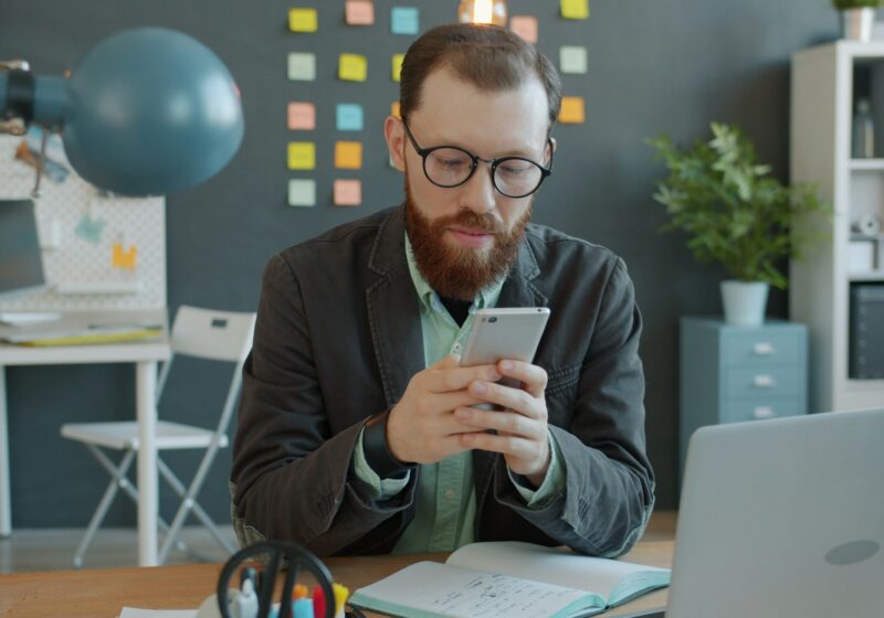 Professional using a smartphone at an office desk