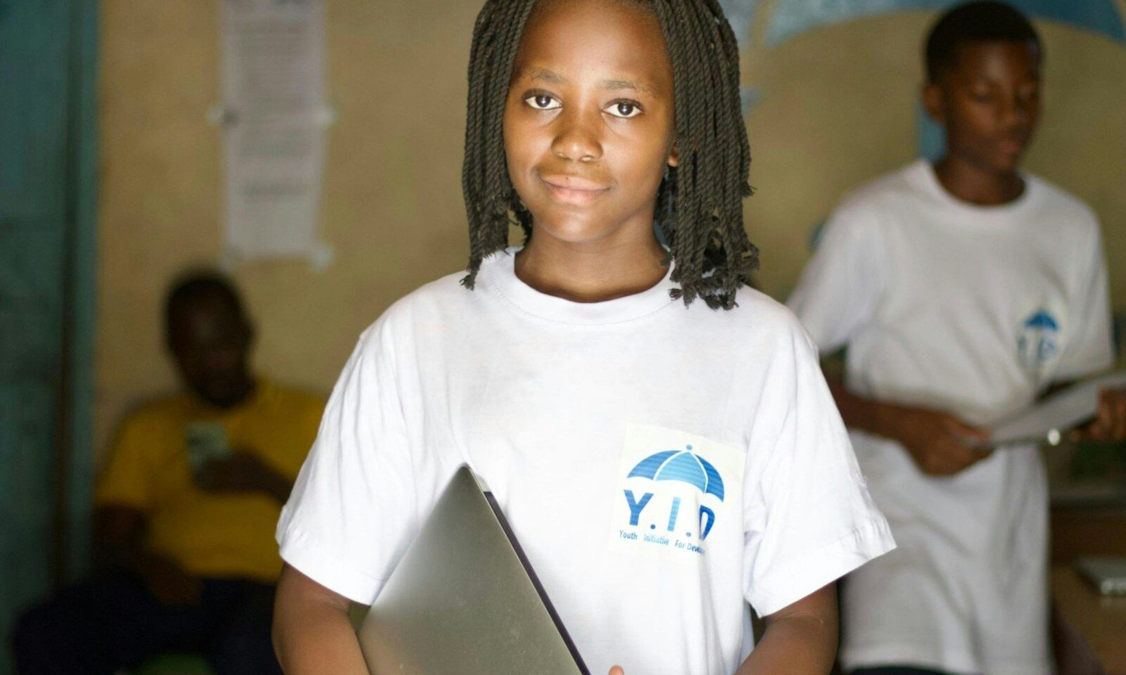 Student holding a laptop in a classroom