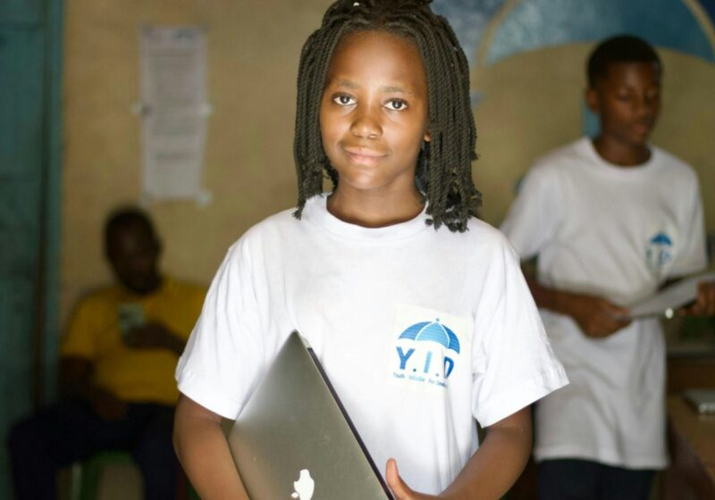 Student holding a laptop in a classroom