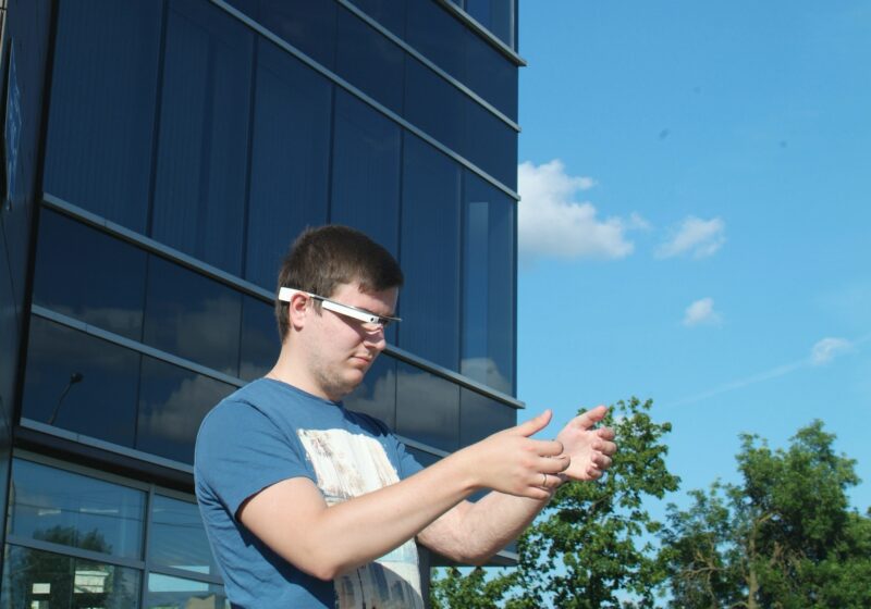 Person interacting with augmented-reality glasses and virtual objects.