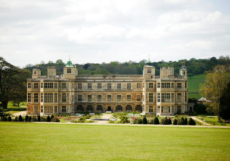 Historic English manor behind a green lawn, illustrating heritage property branding