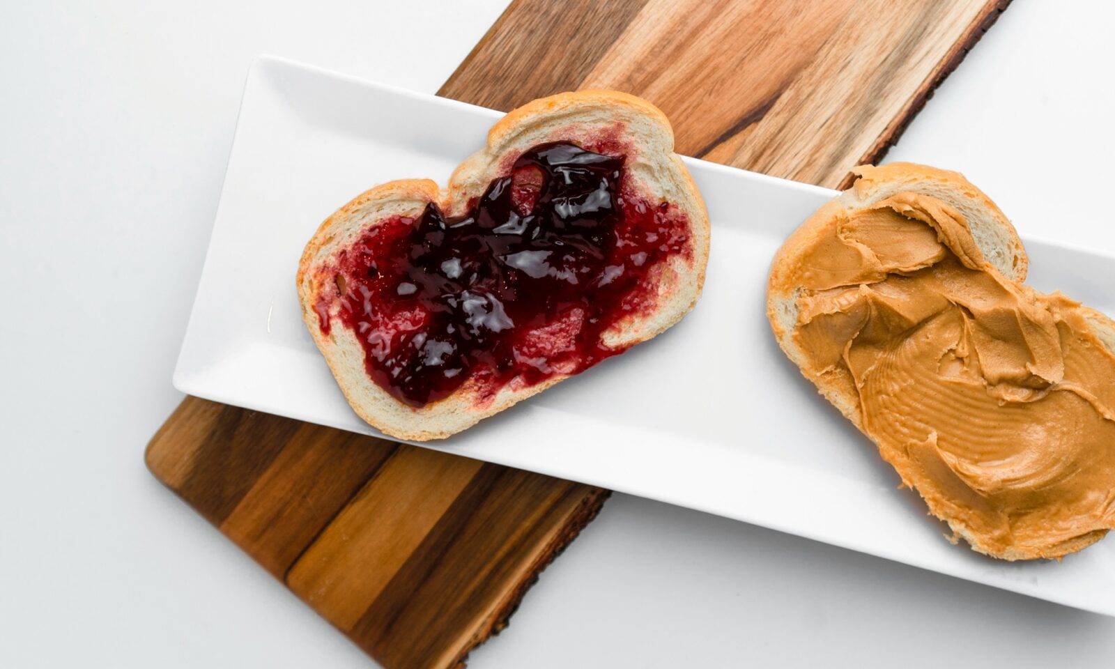 Open peanut butter and jelly sandwich on a white platter