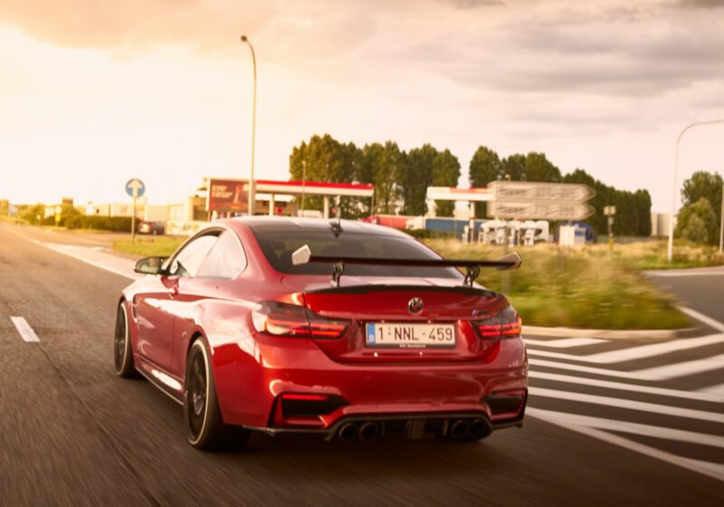 Red sports car traveling on a road, illustrative image