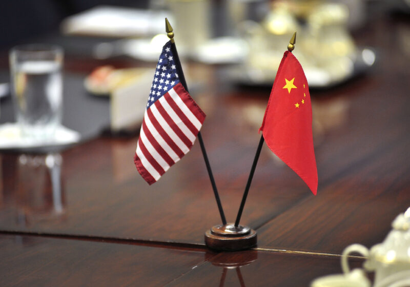 United States and Chinese flags standing together at a meeting table